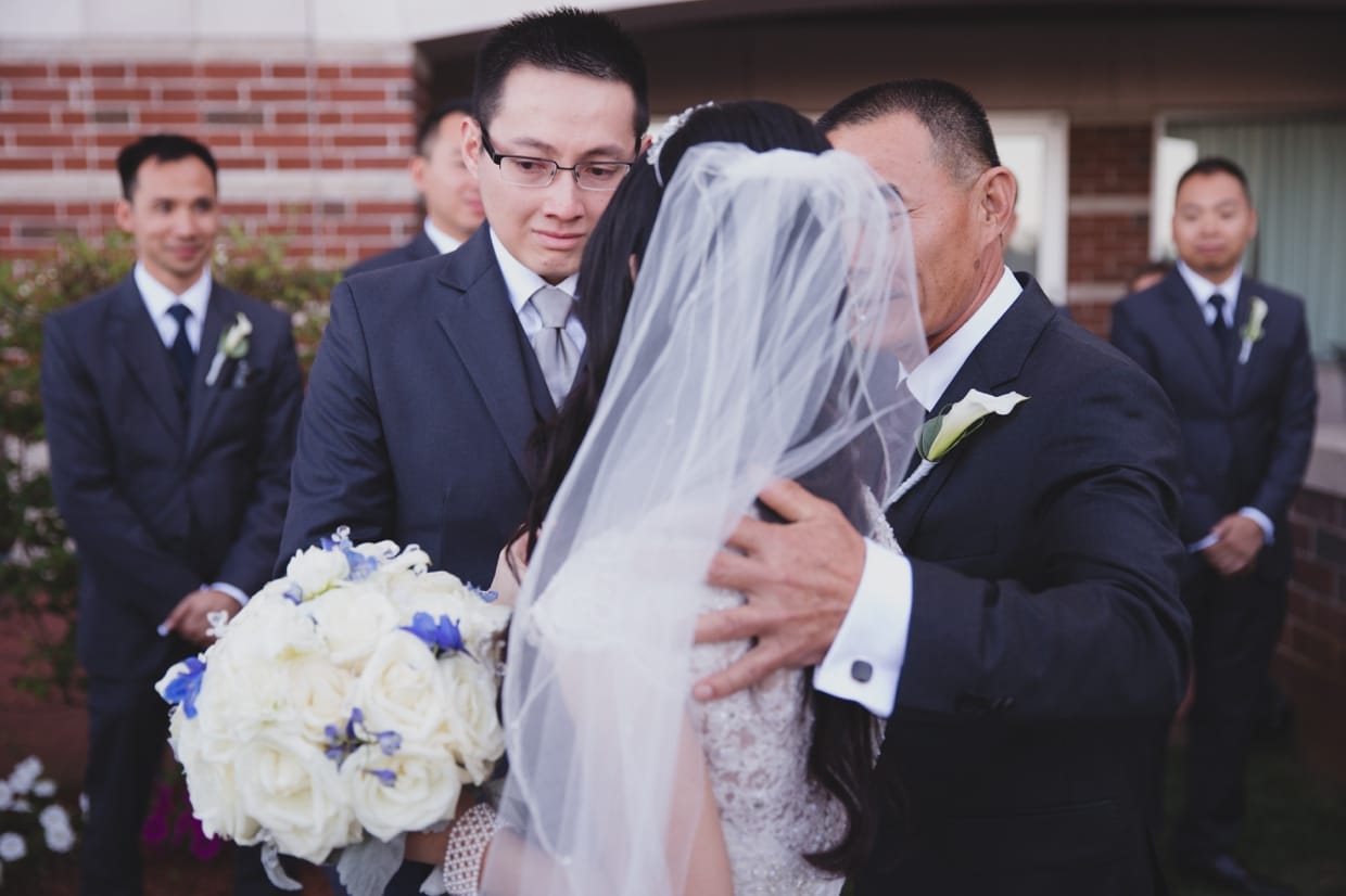 An emotional photograph of a groom crying as he meets his bride at the top of aisle during their wedding ceremony at the Boston Marriott Hotel