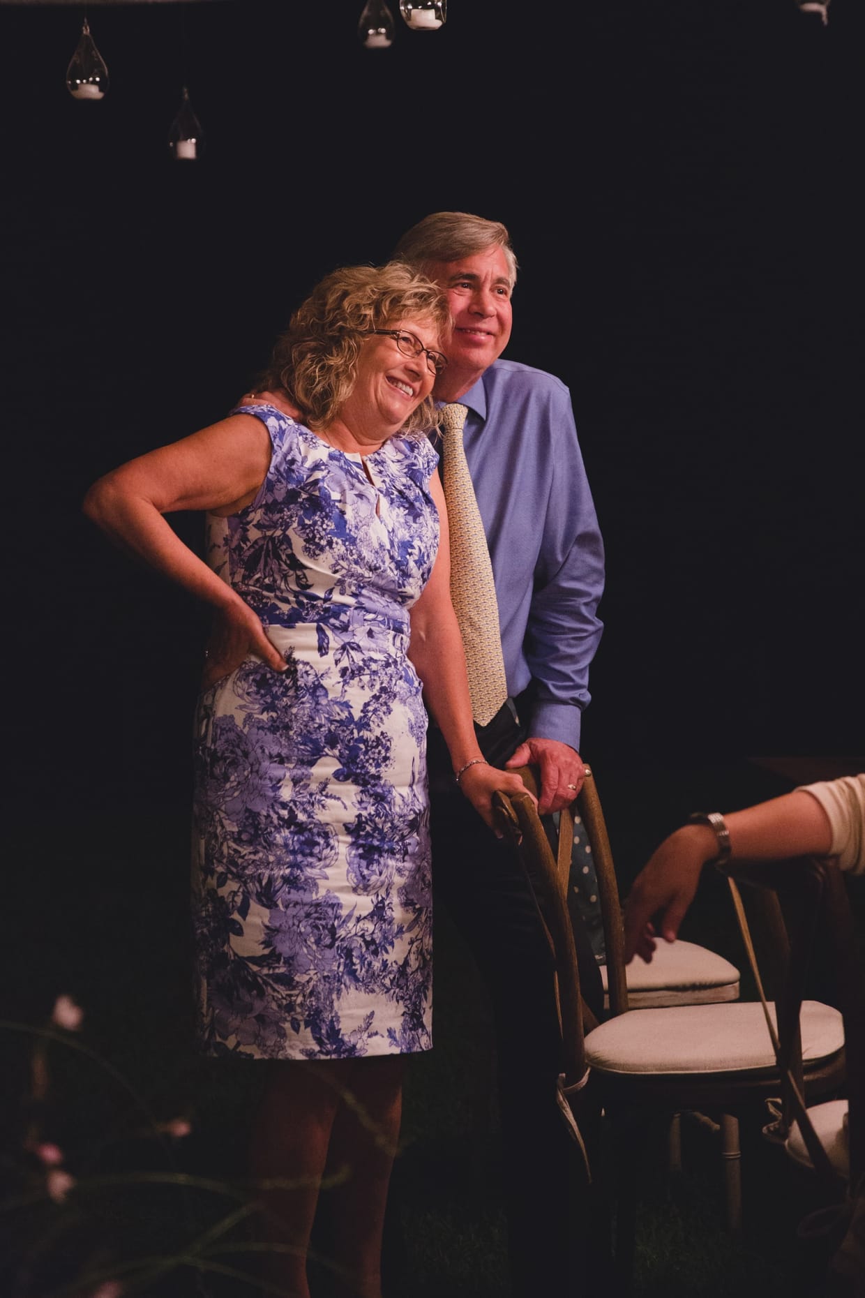 A beautiful candid photograph of the grooms parents smiling during the wedding speeches at a backyard wedding in Massachusetts