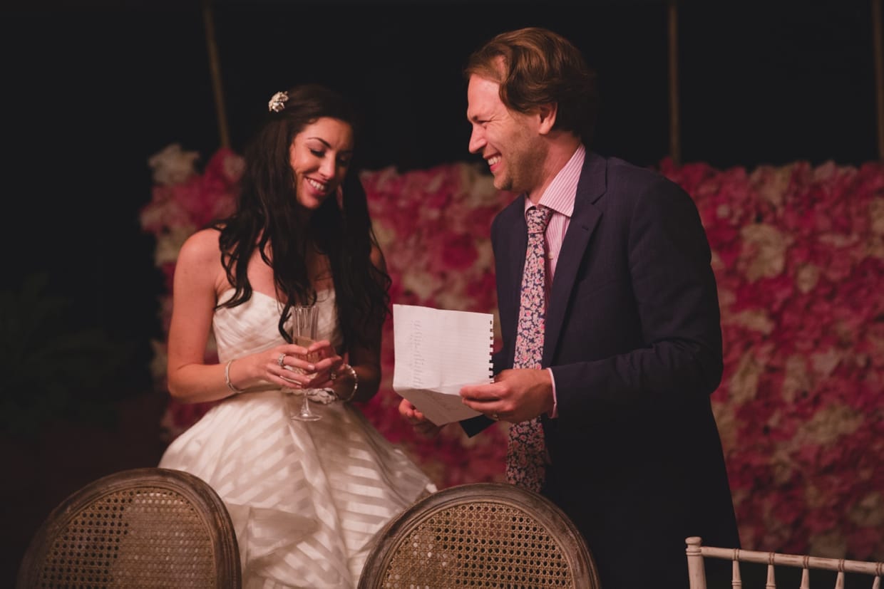 A documentary style photograph of a bride and groom laughing while they play party games at their backyard wedding in Massachusetts