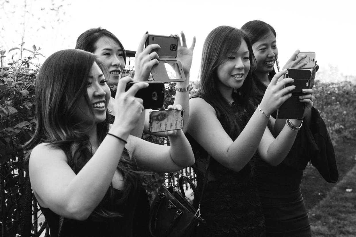 A candid photograph of guest taking pictures of the bride and groom with their phones