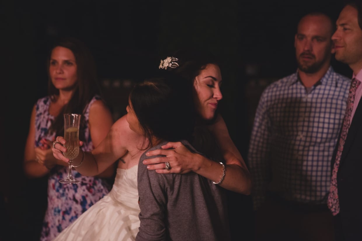 A bride hugs her friend at the end of her backyard wedding in Massachusetts