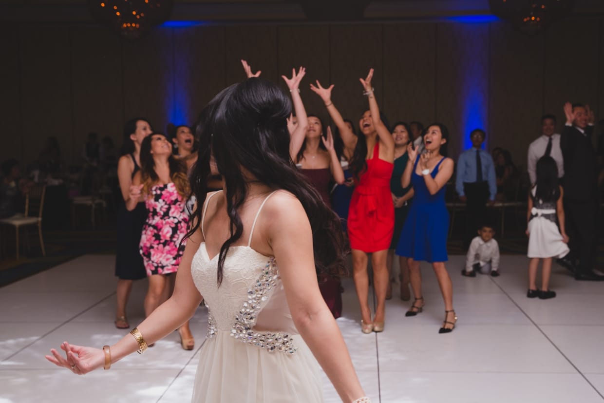 A fun photograph of a bride throwing her bouquet during her wedding at the Boston Marriott Hotel