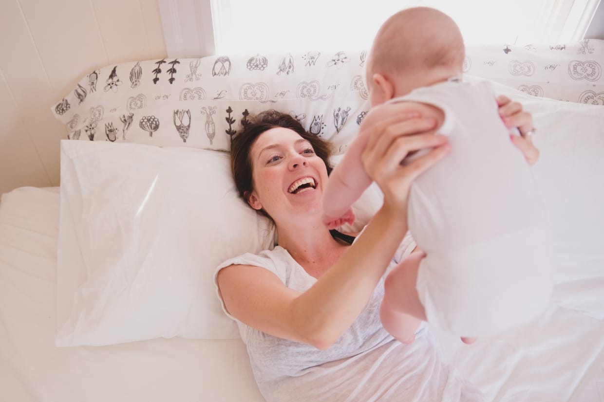 A beautiful photograph of a mother lifting her baby up during an in home family photo session in Boston