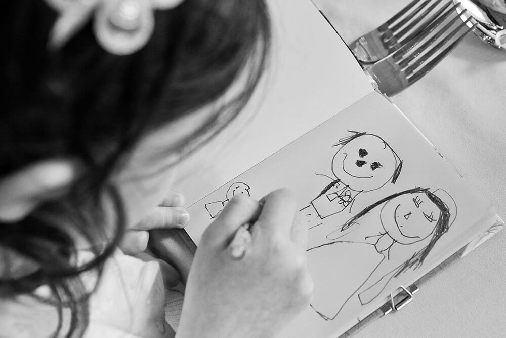 Documentary photograph of the flower girl drawing a picture of the bride and groom during a wedding in Boston, Massachusetts