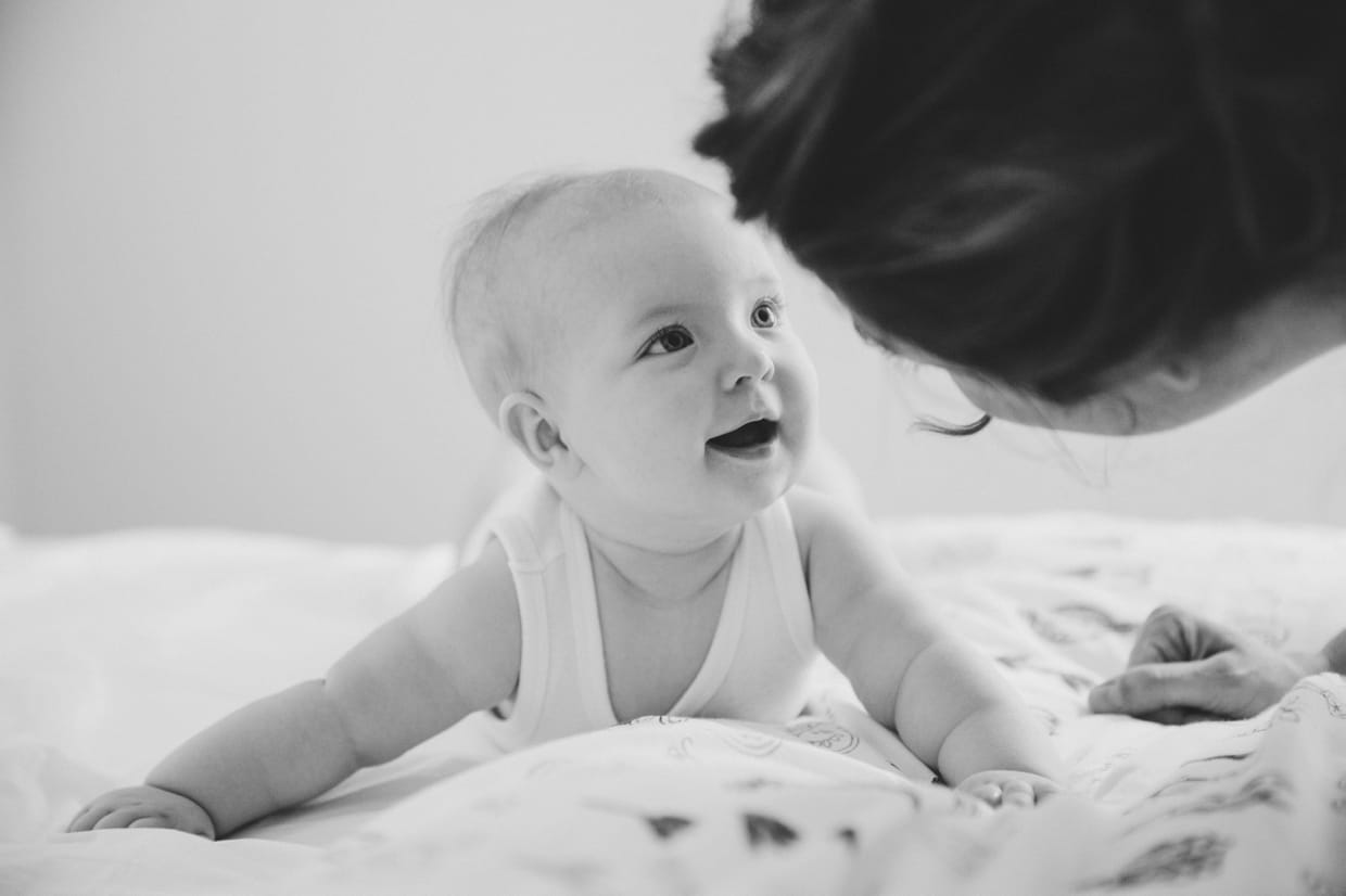 A sweet photograph of a baby looking at her mother during an in home family photo session in Boston