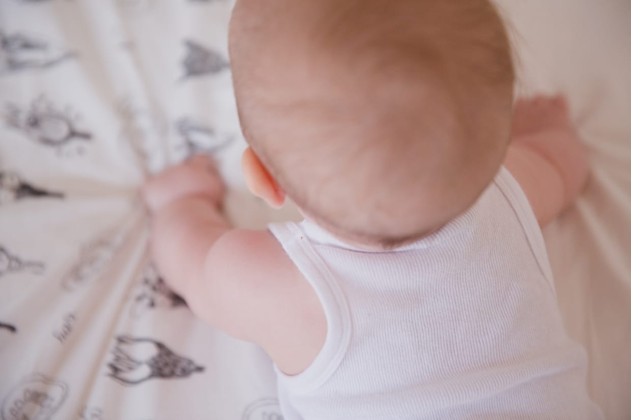 A cute photograph of a baby trying to crawl during a Boston in home family photo session
