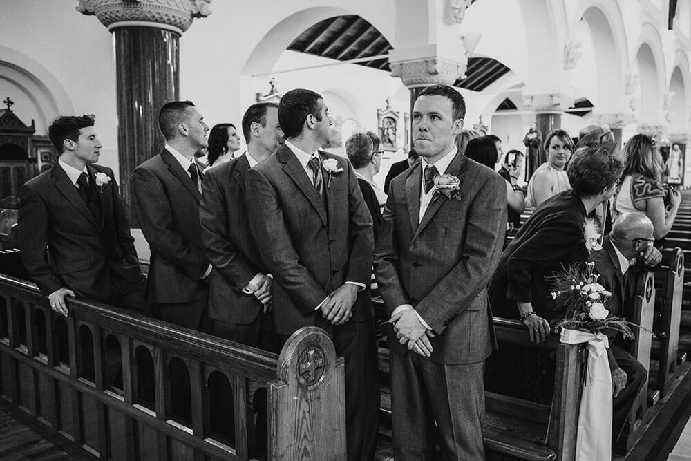 A documentary style photograph of a groom waiting for his bride to walk up the aisle at their Boston Wedding