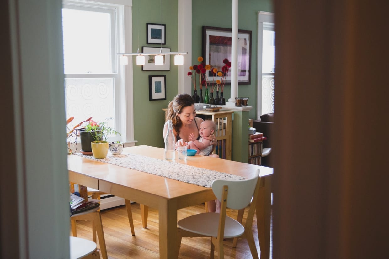 A documentary photograph of a mother feeding her baby during an in home family photo session in Boston