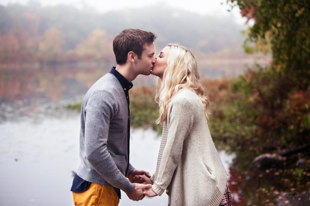 A natural and intimate portrait of couple kissing during their engagement session on the Charles River in Boston