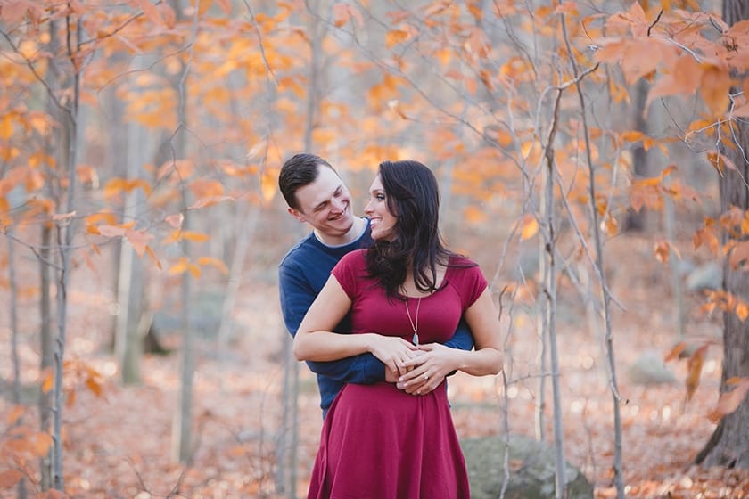 A beautiful and natural portrait of a couple hugging and smiling during their engagement session at the Massachusetts Borderland State Park