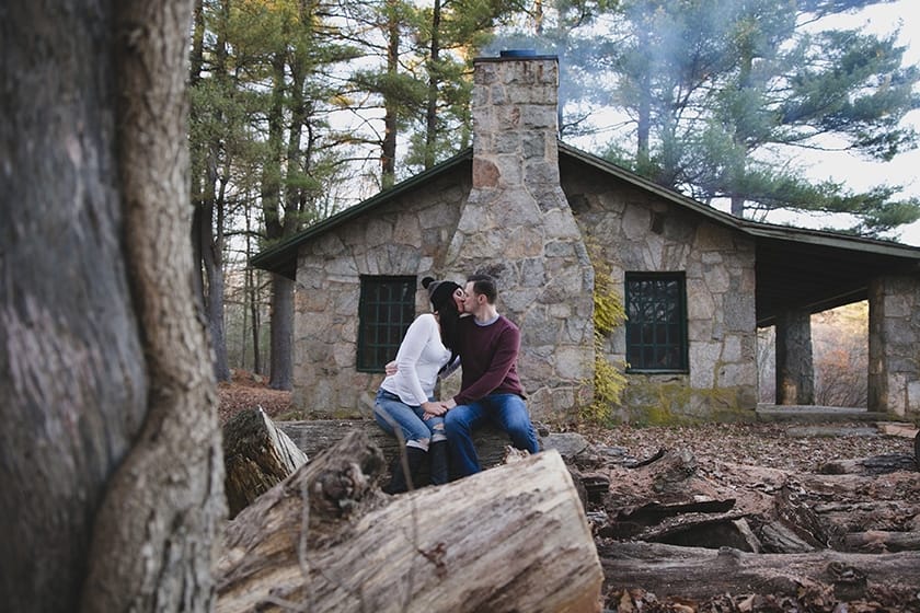 A couple kiss outside a cabin at the Borderland State Park during their New England Engagement Session