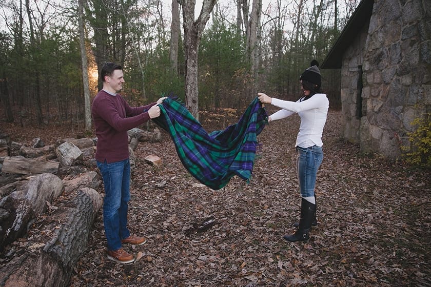A documentary style portrait of a couple folding a blanket during their engagement session at Borderland State Park