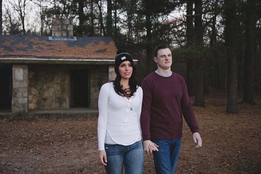 A documentary style photograph of a couple walking away from a cabin during their engagement session at Borderland State Park