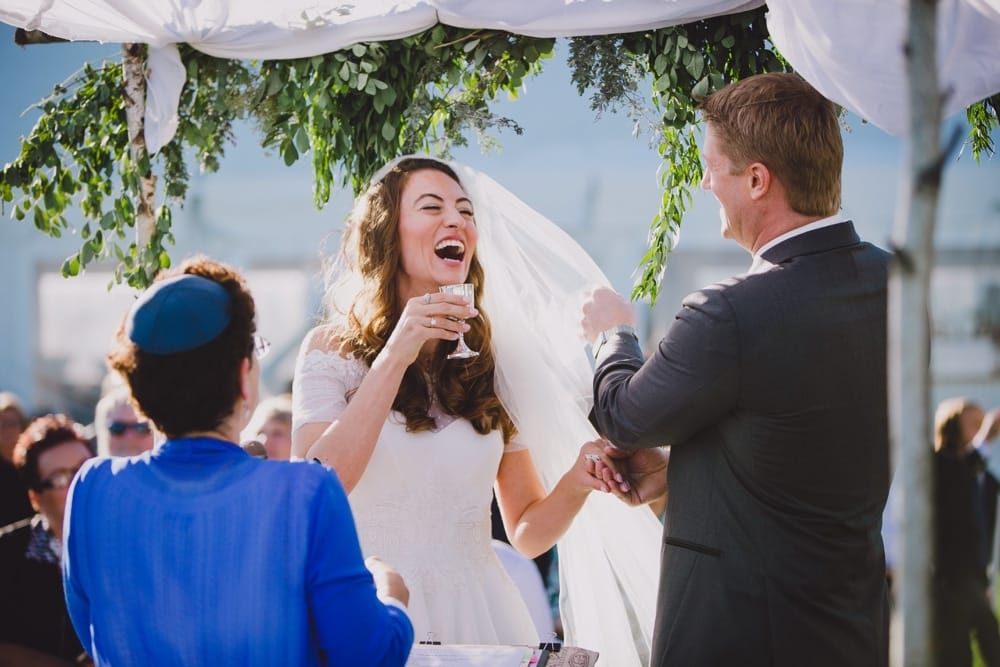 A photojournalistic photograph of a bride laughing during her wedding ceremony on cape cod