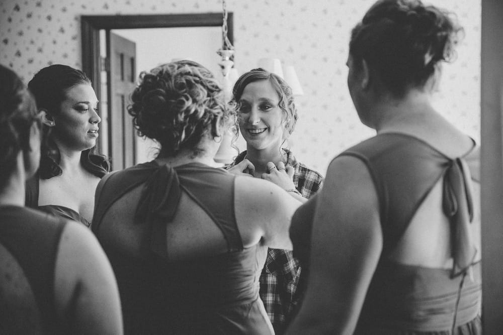 A documentary photograph of bridesmaids helping a bride get ready before her rustic River Club Wedding in Scituate, Massachusetts