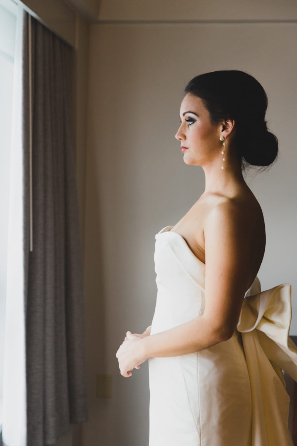A portrait of a bride looking out the window of the Hyatt Regency Hotel before her wedding in Newport, Rhode Island