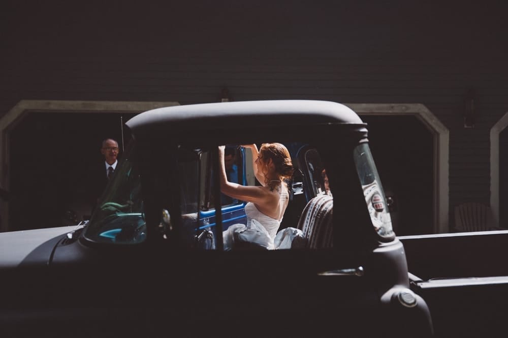 A photojournalistic photograph of a bride getting into her vintage Chevrolet truck before her rustic Massachusetts River Club Wedding in Scituate