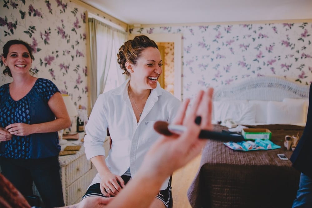 A bride laughs while getting ready at the Governors Inn before her rustic New Hampshire barn wedding at Kitz Farm