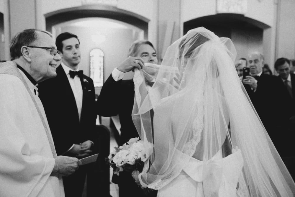 A photojournalist photograph of a father lifting his daughter veil during her wedding ceremony at St. Augustin's Church in Newport, Rhode Island