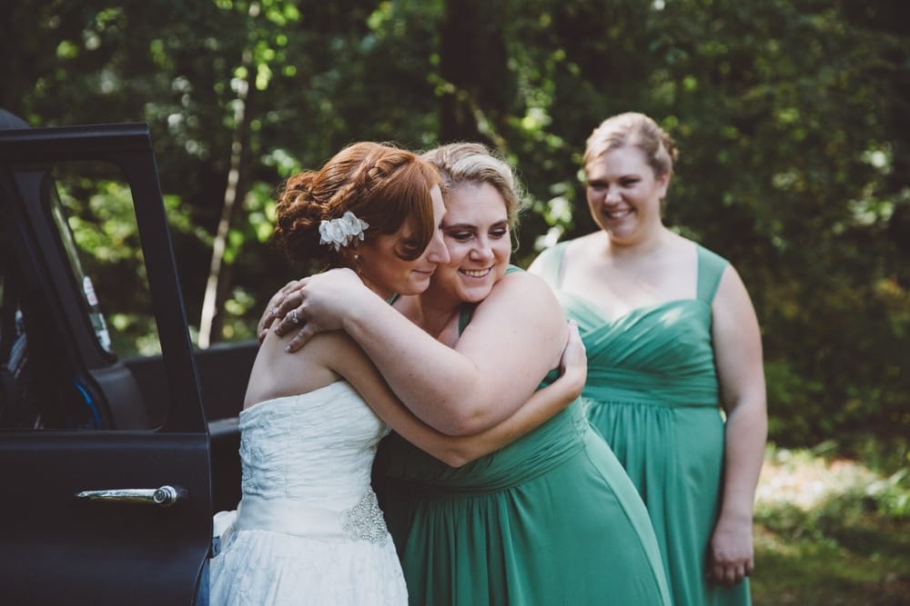 A photojournalistic portrait of bride hugging her bridesmaids during a rustic River Club Wedding in Scituate, Massachusetts