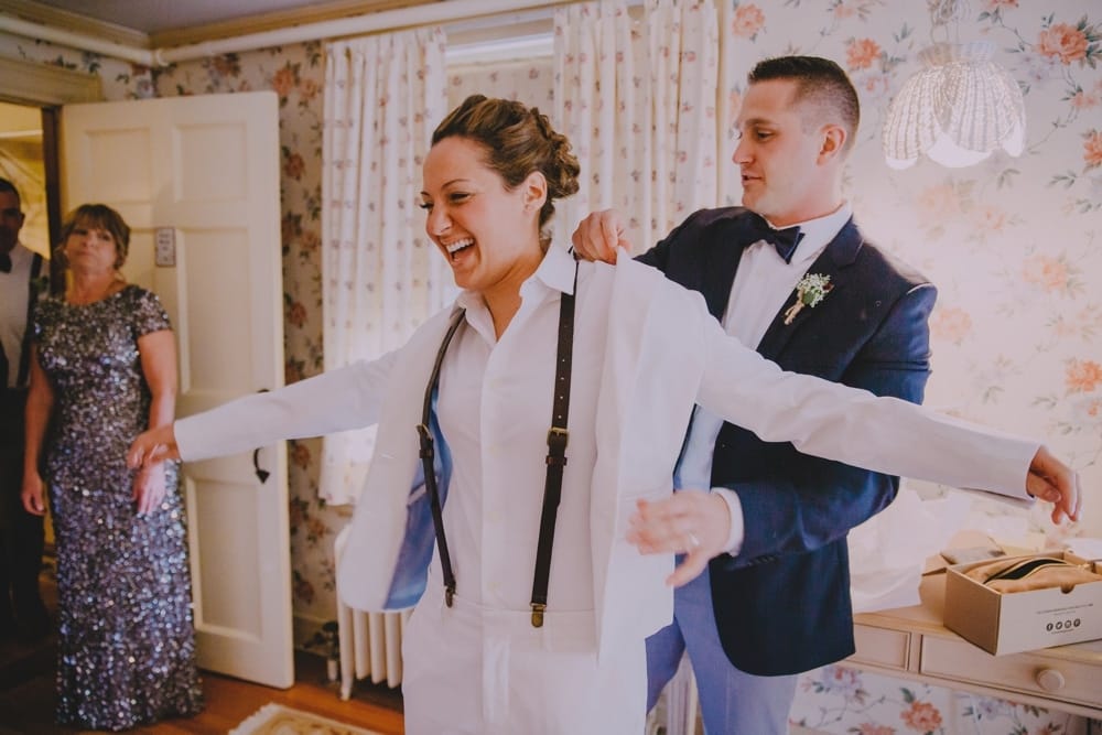 A documentary photograph of a bride's maid of honor helpiing her put on her jacket before her rustic barn wedding at Kitz Farm in New Hampshire