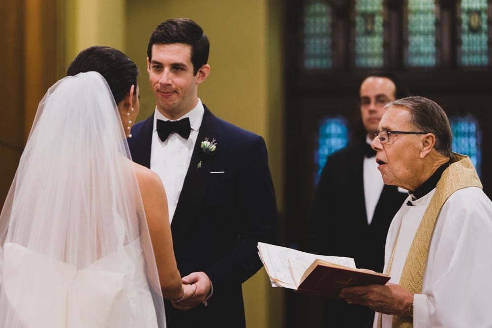 A documentary photograph of a bride and groom saying their wedding vows at St. Augustin's Church in Newport, Rhode Island