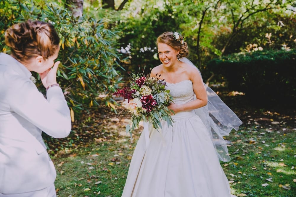 A documentary photograph of a bride seeing her bride during their first look before their rustic New Hampshire barn wedding at Kitz Farm