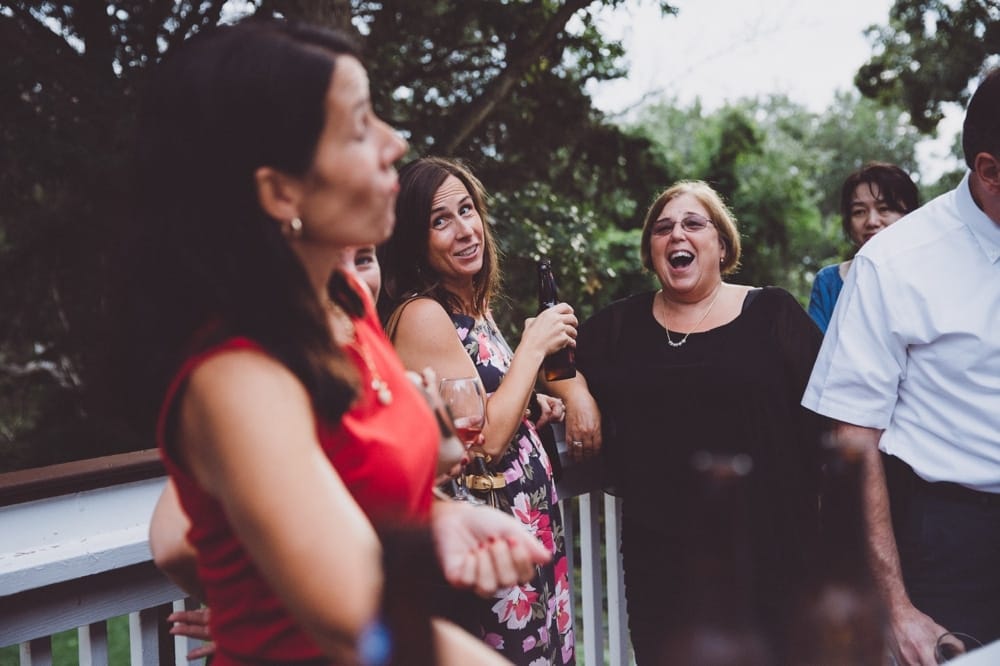 A documentary photograph of wedding guests laughing during cocktail hour at the River Club in Massachusetts