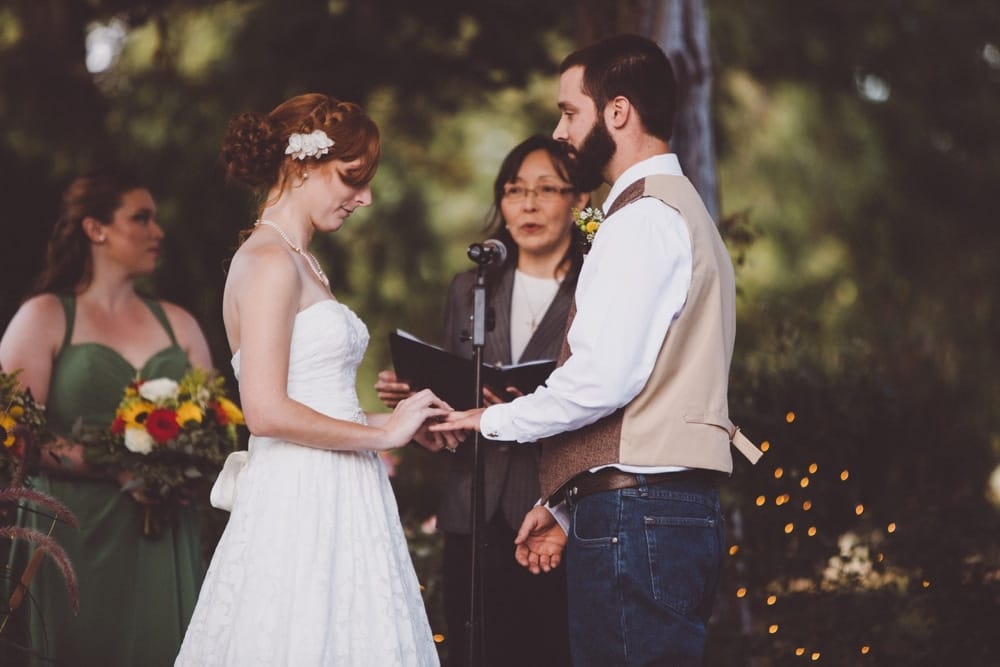 A documentary photograph of a bride placing a ring a her groom's finger during their intimate and rustic River Club Wedding in Scituate, Massachusetts