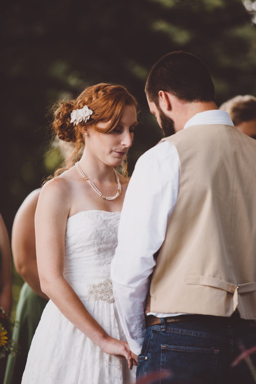 A emotional documentary photograph of a bride and groom saying a pray during their intimate and rustic River Club Wedding ceremony in Scituate, Massachusetts
