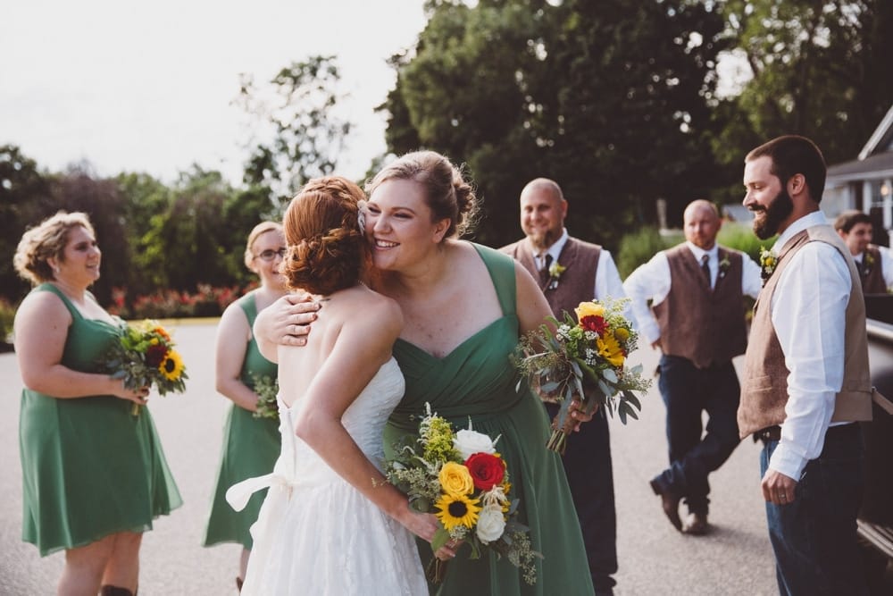 A documentary photograph of a bridesmaid hugging the bride after her River Club Wedding ceremony in Scituate, Massachusetts