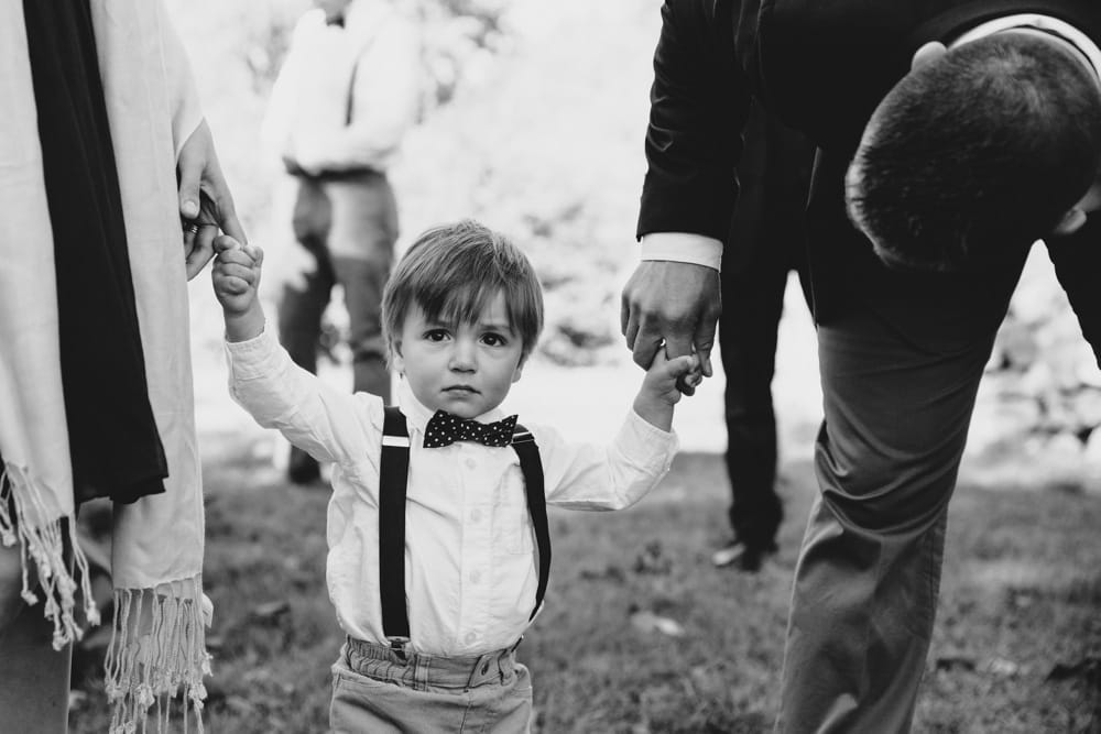 A photojournalistic photograph of a ring bearer moments before he walks down of the aisle during a rustic outdoor Kitz Farm wedding ceremony in New Hampshire
