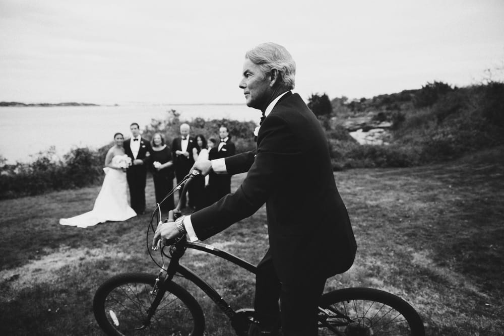 A documentary photograph of a man riding a bicycle during a wedding reception at the Castle Hill Inn in Newport, Rhode Island