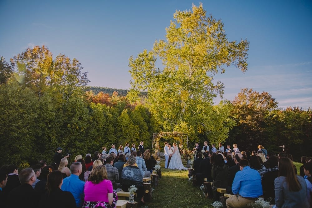 A photojournalistic photograph of a rustic outdoor wedding ceremony at Kitz Farm in the fall in New Hampshire