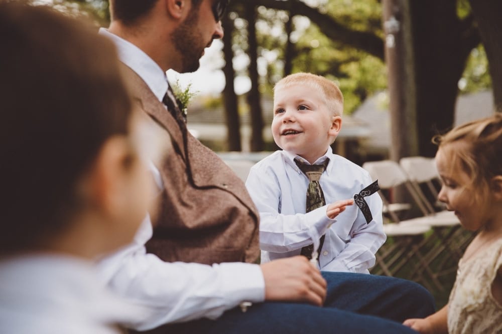 A photojournalistic photograph of kids playing with a groomsman during a rustic outdoor River Club Wedding in Scituate, Massachusetts