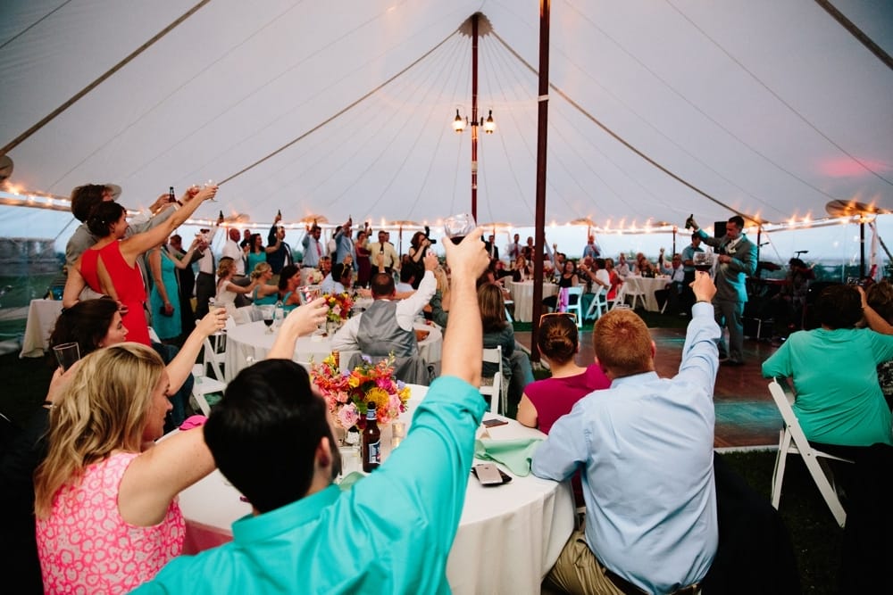 A documentary photograph of wedding guest toasting the bride and groom during a wedding at Pilgrims Monument in Provincetown, Cape Cod