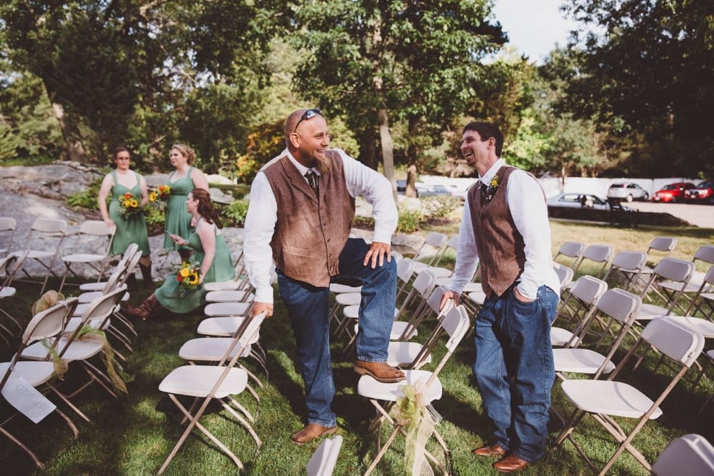 A photojournalistic photograph of bridesmaids and groomsmen waiting around during the family portraits at a rustic outdoor River Club Wedding in Scituate, Massachusetts