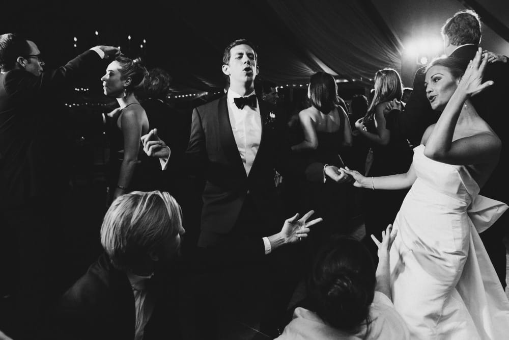 A photojournalistic wedding photograph of a bride and groom dancing with their guest at the Castle Hill Inn in Newport, Rhode Island