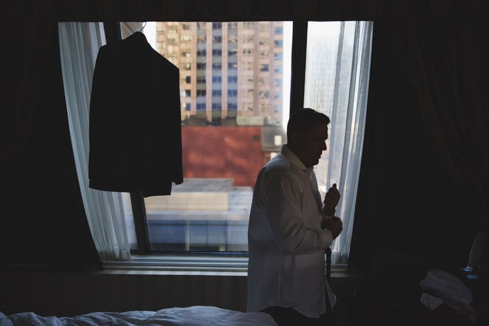 A documentary and artistic photograph of a groom getting ready at the Langham Hotel before his wedding at the State Room in Boston, Massachusetts