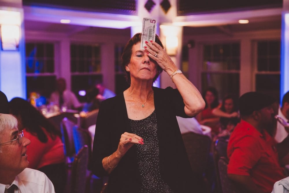 A funny documentary photograph of a wedding guest playing games during a relaxed River Club Wedding in Scituate, Massachusetts