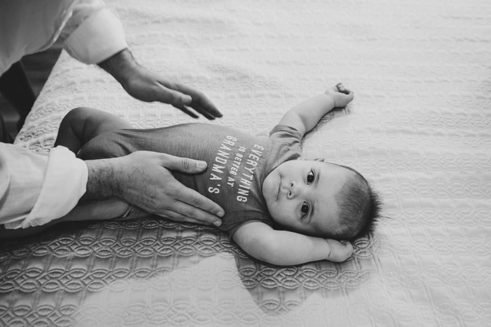 A documentary photograph of a baby being changed after his nap during an in home lifestyle family photo session in Boston, Massachusetts