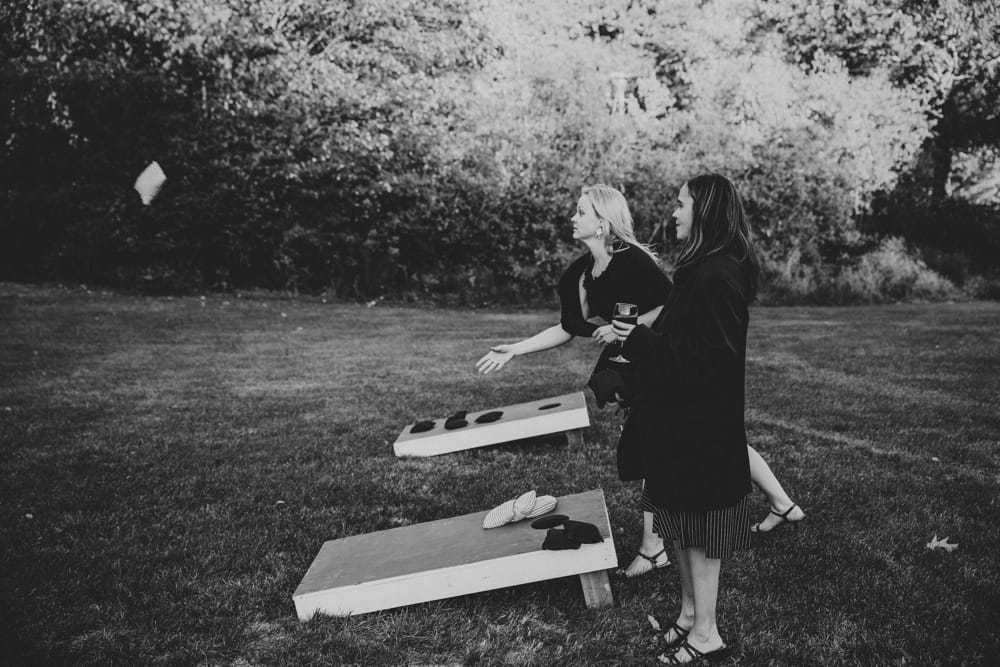 A documentary photograph of two ladies playing lawn games during a rustic New Hampshire barn wedding at Kitz Farm