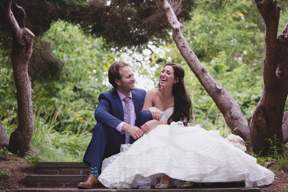 A candid wedding portrait of a bride and groom laughing at Minute Man Park in Concord, Massachusetts