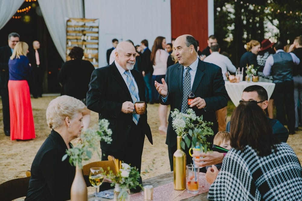 A documentary photograph of wedding guests enjoying a laid back cocktail hour at a rustic New Hampshire barn wedding at Kitz Farm