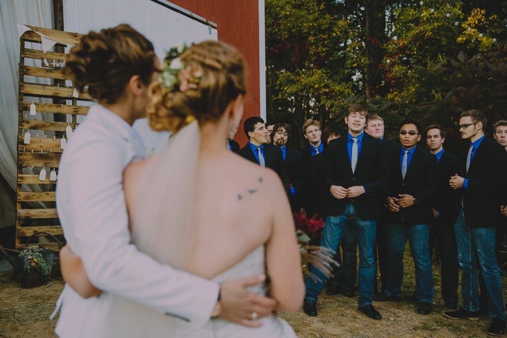 A documentary photograph of two brides enjoying the music during their rustic New Hampshire barn wedding at Kitz Farm in New Hampshire