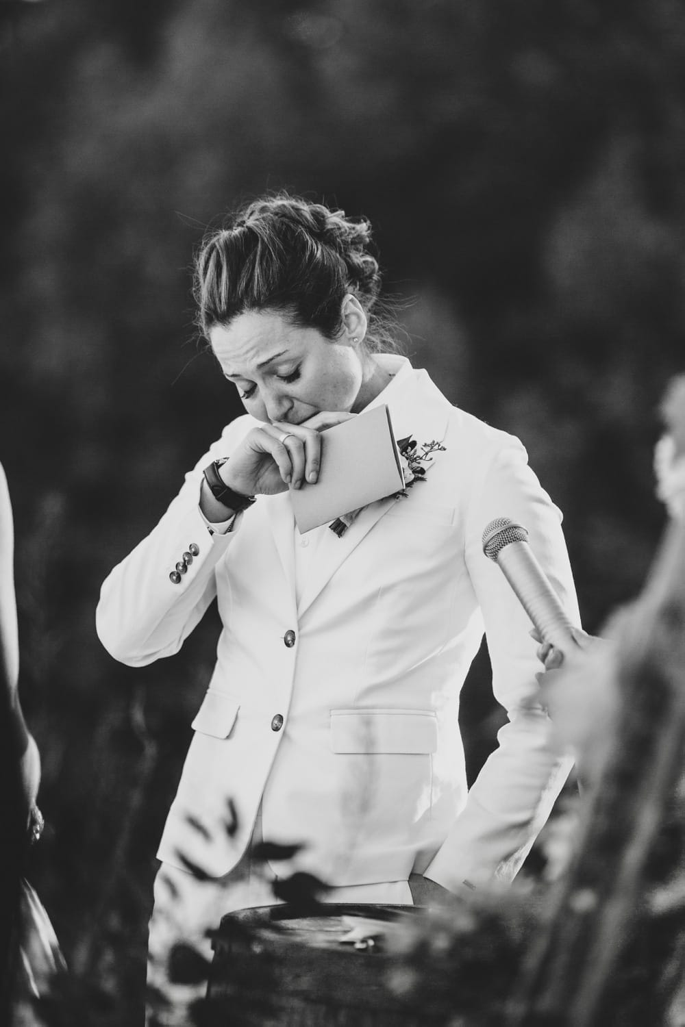 A beautiful and emotional documentary photograph of bride holding back tears as she reads her vows to her bride to be during an outdoor wedding ceremony at Kitz Farm in New Hampshire