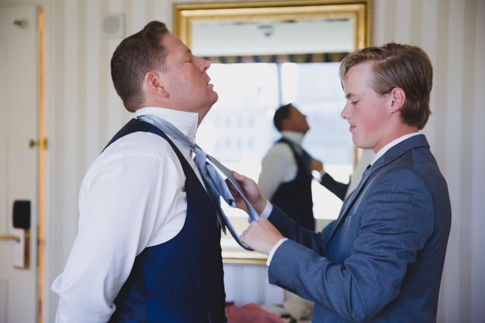 An emotional documentary photograph of groom getting ready at the Langham Hotel before his wedding at the State Room in Boston, Massachusetts