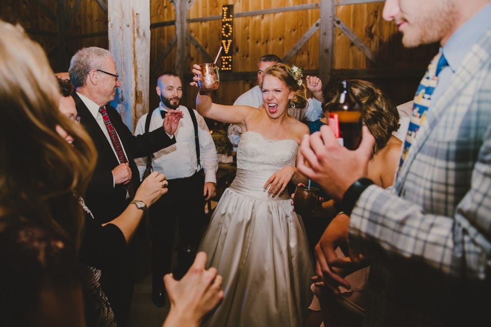 A bride celebrates with friends during her rustic barn wedding at Kitz Farm in New Hampshire