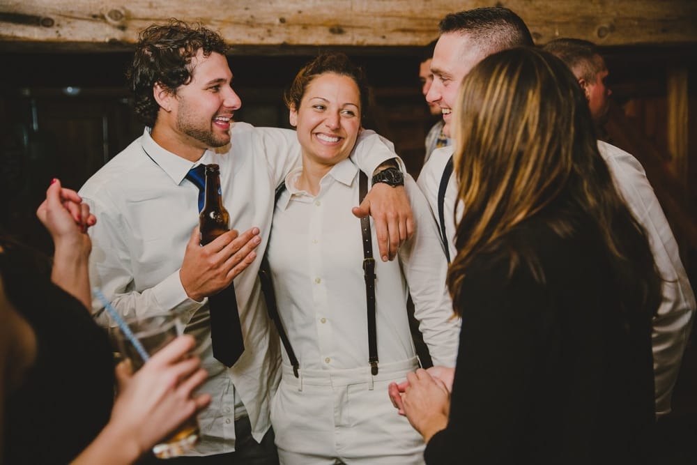 A photojournalistic photo of a bride talking and laughing with wedding guest during her rustic New Hampshire barn wedding at Kitz Farm