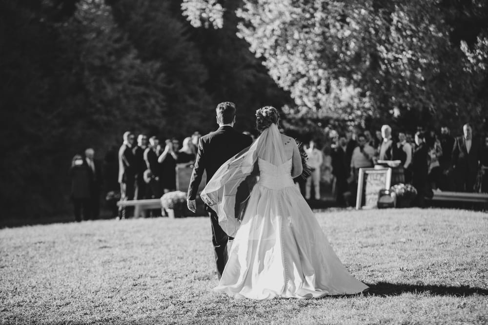 A documentary photograph of bride walking up the aisle with her father at a beautiful outdoor ceremony at Kitz Farm in New Hampshire